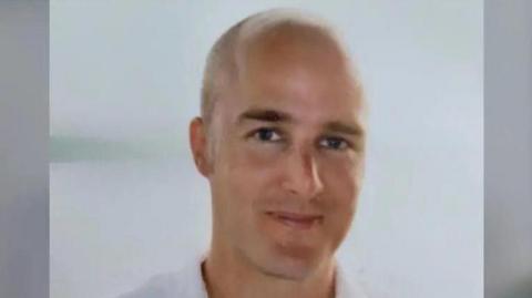 A head and shoulders shot of Alexander Cashford shows a balding man who is smiling.