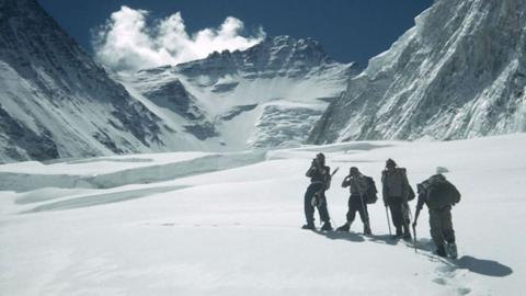 Four people walking on a snow covered mountain