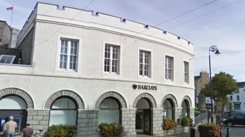 The outside of the building, which is curved and has large arched windows on the ground floor and a castellated roof.