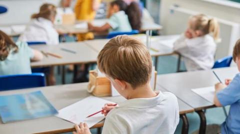 Back of head of a boy at a table looking at a notebook