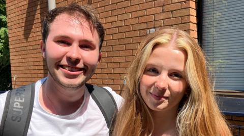 A male university student and a female university student standing next to each other.