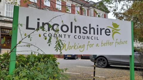 A sign outside a public building which says "Lincolnshire County Council, working for a better future".