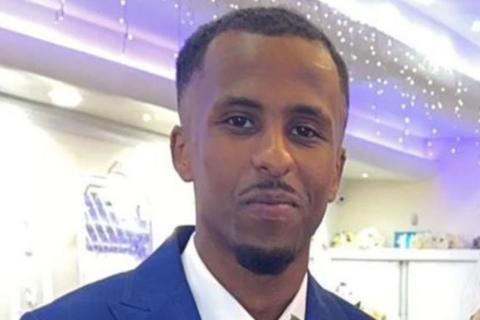 Mahad Abdi Mohamed, who has a small goatee beard, wearing a blue suit, looking at the camera