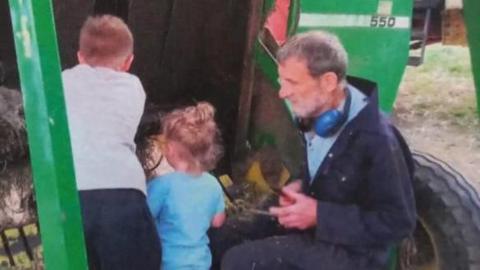 Family handout image showing John Charlesworth with two children beside a tractor.