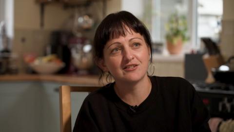 Parent Celeste Lewis sitting in a kitchen