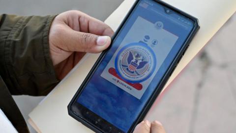 A migrant holds a phone displaying the CBP One app, which was used for migrants at the US southern border to apply for potential legal status.