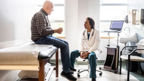 Doctor and male patient discussing treatment in exam room

