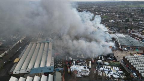 Aerial view of a large plume of grey smoke emitting from a factory