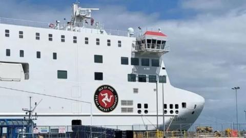 A close up of the Manxman, a large boxy white ferry with the three legs of man on the side.