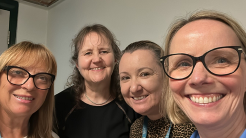 Four women – two of them wearing glasses – smiling at the camera.