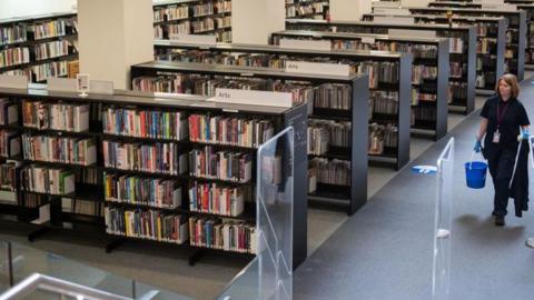 A woman cleaning in a library. Stock photo.