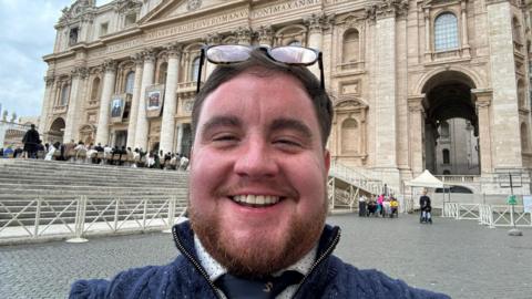 George White, a transgender man, smiles standing in a plaza outside the vatican church in Rome 
