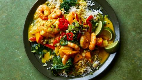 prawn curry in a dark bowl on a green surface