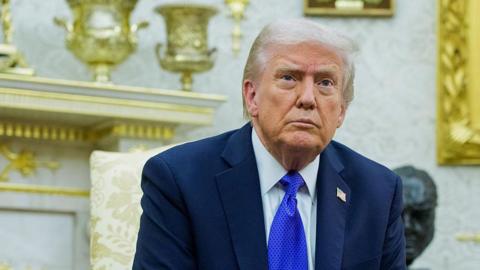 A close-up photo of US President Donald Trump with a stern look during a meeting in the White House's Oval Office.