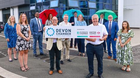 Steve Gates (left), vice chairman of the new Devon Chamber, and Richard Stevens, chairman of the Devon Chamber, holding a sign to mark the creation of the Devon Chamber with another 10 people associated with the Devon Chamber