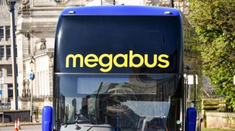 A close up of a Megabus coach. The livery is blue with yellow branding.