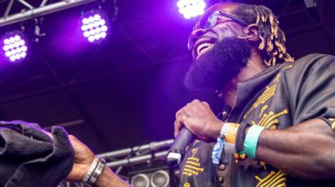 A musician on stage laughing and holding a microphone