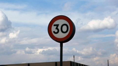 A 30mph speed limit sign. Behind it is a blue sky with white clouds. 