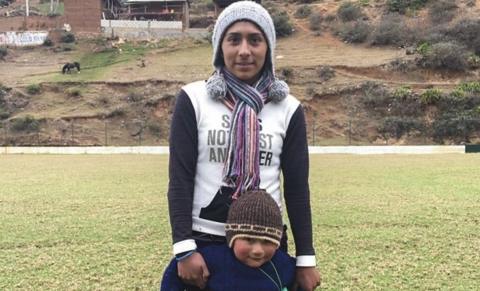 A mother in Peru stands behind her child