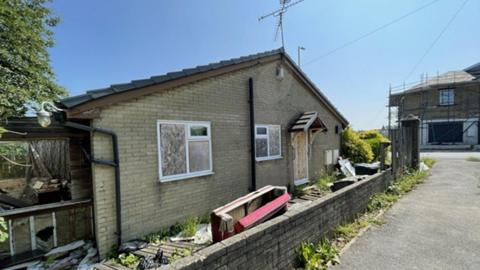 Exterior shot of a run down, derelict bungalow on Park Lane in Bradford