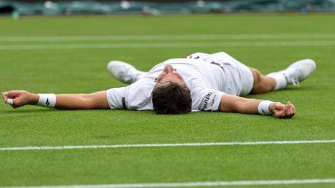 Cameron Norrie celebrates by falling on to the court 