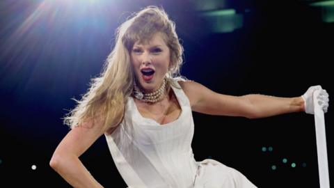 Taylor Swift wears white dress on stage at concert