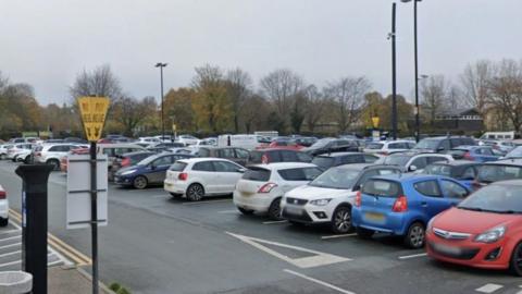 A Shropshire Council car park, with hundreds of cars parked. There is a black ticket machine on the left, with a yellow sign that says "pay here".