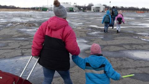 Migrant families come and go from the Floyd Bennett Field migrant shelter on December 25, 2024, in the borough of Queens, New York City