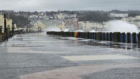 Waves crashing against the railings on Douglas Promenade walkway.