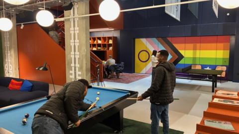 Two people playing pool in a colourful lobby