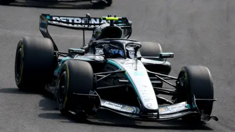 Mercedes' Kimi Antonelli winks while clasping hands with someone who is out of shot before the Japanese Grand Prix