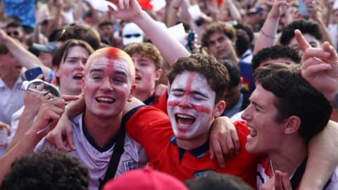 England football fans with St George's crosses painted on their faces at a fanzone