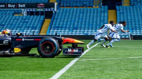 Leeds United players race against a Red Bull F1 car