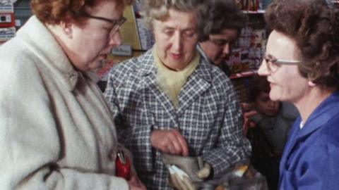 Three women holding purses stand together