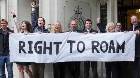 A number of people celebrating behind a banner that says "right to roam"