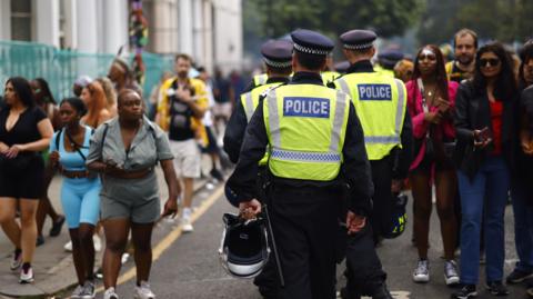 Police officers walking through a small crown of people at the carnival