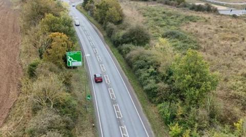 An aerial of the A47 in Norfolk. A green road sign points straight ahead of Great Yarmouth and Norwich whereas to the right it says Mattishall and Honingham. 