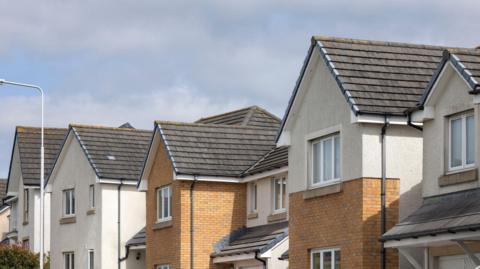 Row of houses with cream walls and orange bricks.