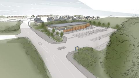 An artist's impression of the new store. It shows a grey road, with a wide turning into a car park and a brown building. There is lots of greenery around the edge.