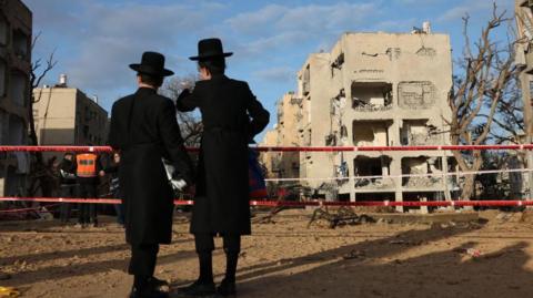 Ultra Orthodox Jewish residents look on at the scene of a direct hit of an Iranian missile in Arad, Israel.