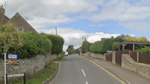 A Google Maps image showing a residential road with houses either side and double yellow lines on the right hand side