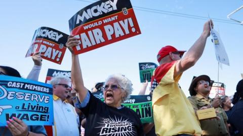 Disneyland workers hold up placards on a protest