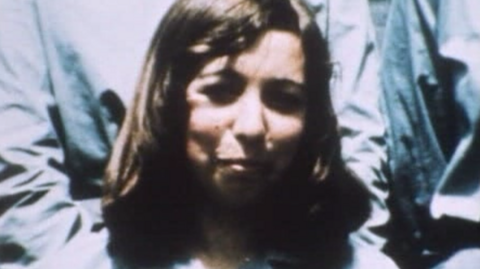 An old colour photograph of a young woman with long brown hair.