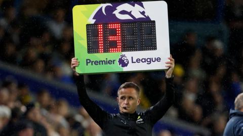 A fourth official holds up the board for additional time