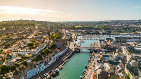 An aerial view over Weymouth showing the harbour and houses stretching to the horizon.