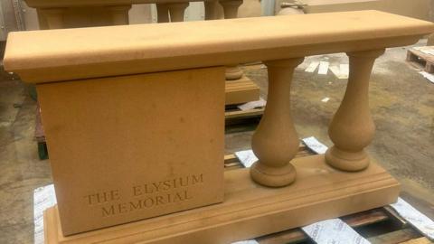 An image of the Elysium Memorial showing a stone structure engraved with the foundations name. On the right of the image are two columns supporting the structure.