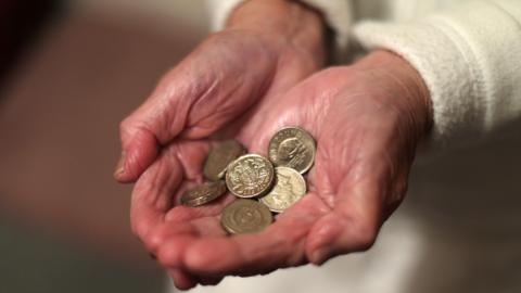 An elderly woman holding pound coins in her hands