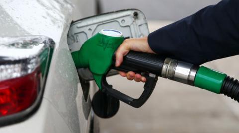 A picture of a person putting unleaded petrol into a silver car.