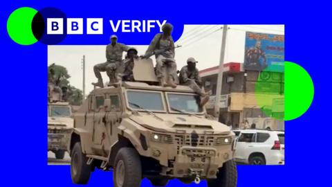 RSF fighters ride on an armoured truck in the city of Nyala. One of the fighters is carrying an assault rifle. All are dressed in military fatigues.