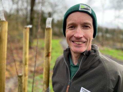 James Ravine standing next to saplings inside tree guards